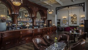 Zona de bar con decoración de madera, sillones de cuero y una mesa de mármol.