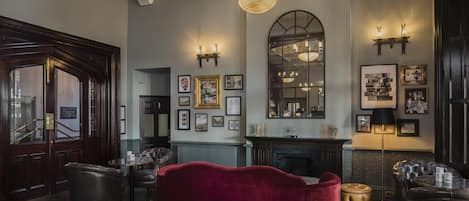 Un salon spacieux avec un grand canapé rouge, une cheminée et un lustre.