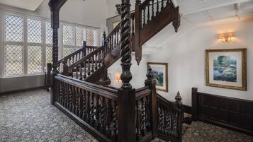 A grand staircase with ornate woodwork and a patterned carpet.