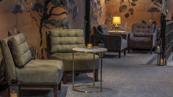 A cozy room with a sofa, armchairs, and a small table with a lamp.