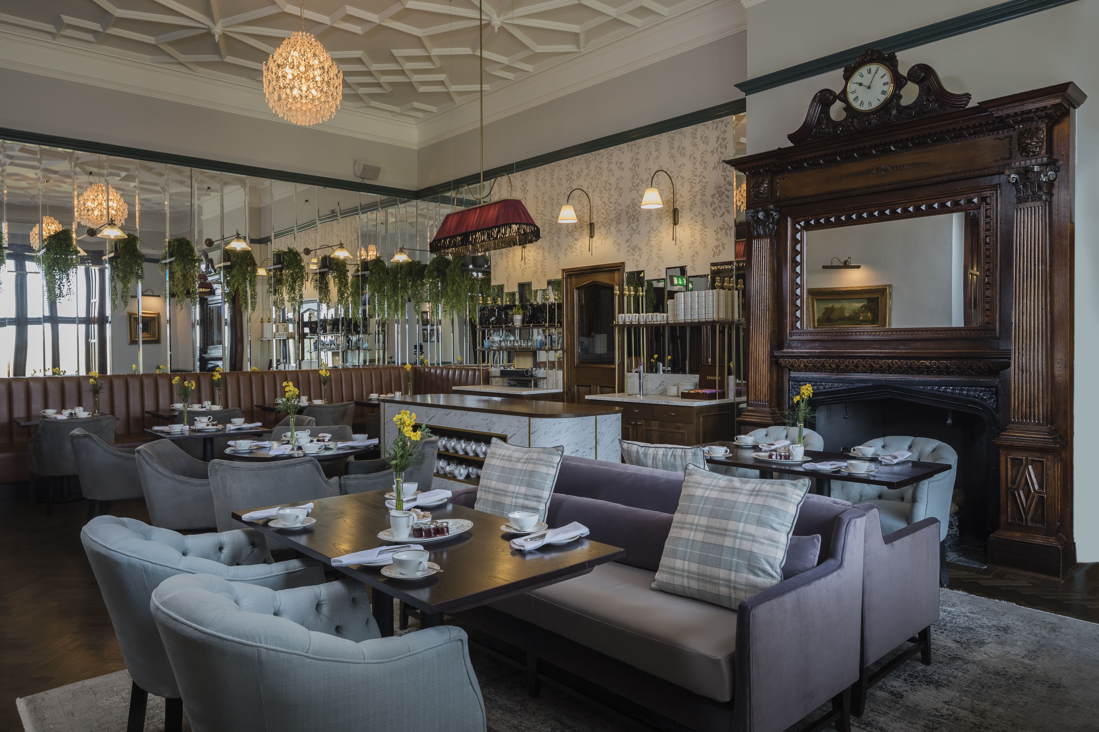 A spacious dining area with high ceilings, hanging chandeliers, and a fireplace.