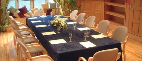 A conference room with a long table, chairs, and a floral centerpiece.