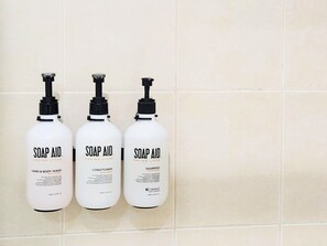 Three white bottles of Soap Aid products on a tiled wall.