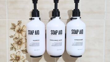 Três frascos de produtos Soap Aid em frente a uma parede de azulejos.