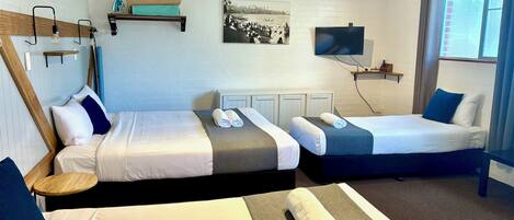Habitación de hotel con dos camas, televisión, un cuadro en la pared y una ventana con cortinas.