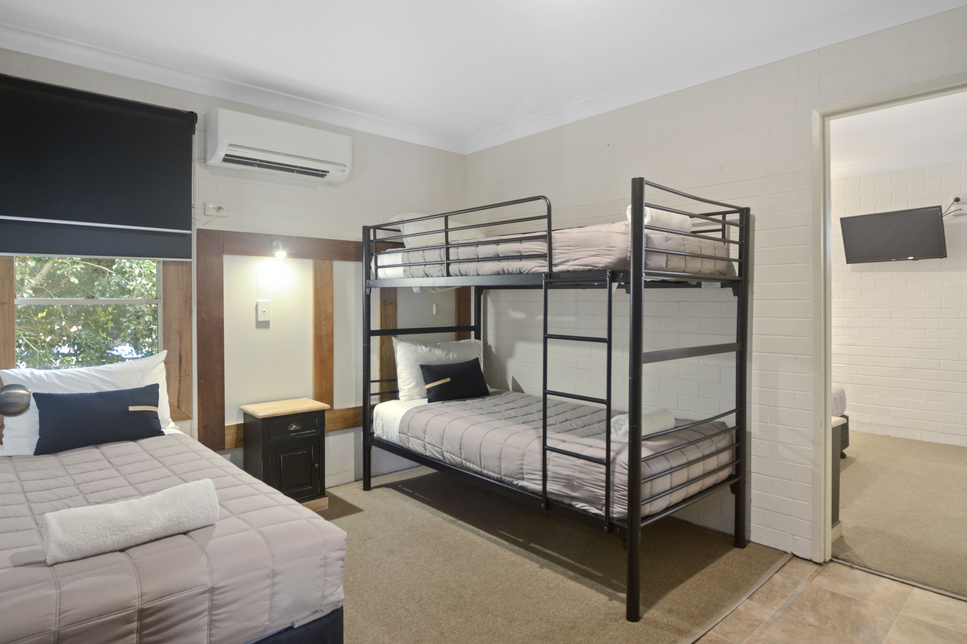 A room with bunk beds, a small desk, and a TV mounted on the wall.