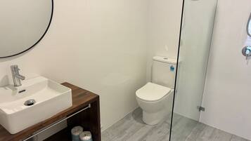 A bathroom with a white sink, mirror, and toilet.