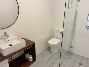 Un baño con lavamanos, espejo e inodoro blancos.