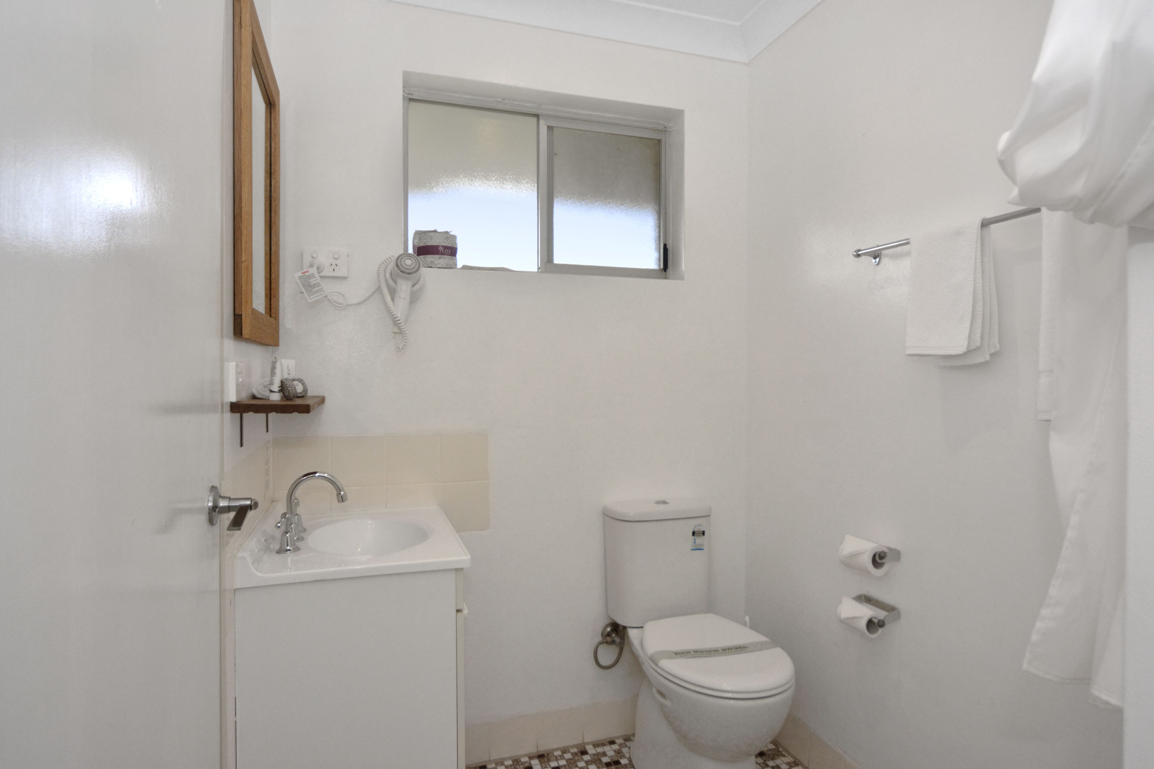 Et lille, rent badeværelse med toilet, vask og vindue.