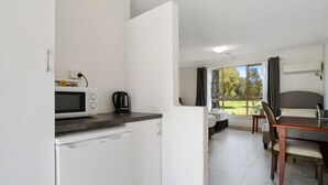 Una cocina compacta con microondas, tetera y un pequeño comedor con mesa y sillas.