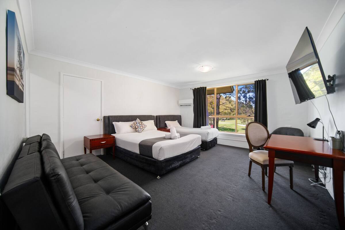 A hotel room with a large bed, a sofa, a desk, and a TV.