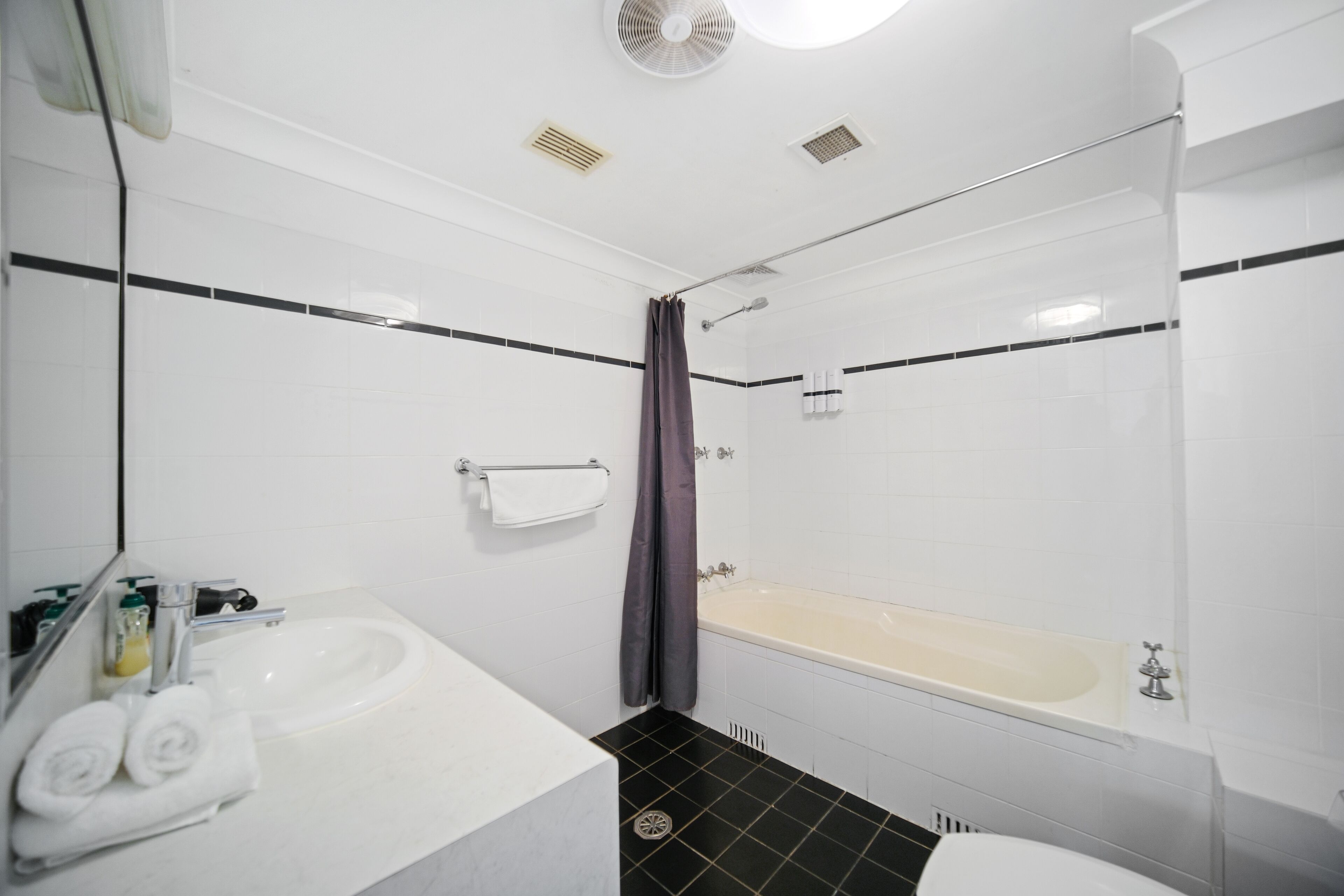 A bathroom with a white sink, a bathtub, and a shower curtain.