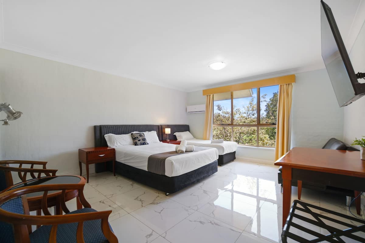 A hotel room with a large bed, two bedside tables, a desk, and a chair.