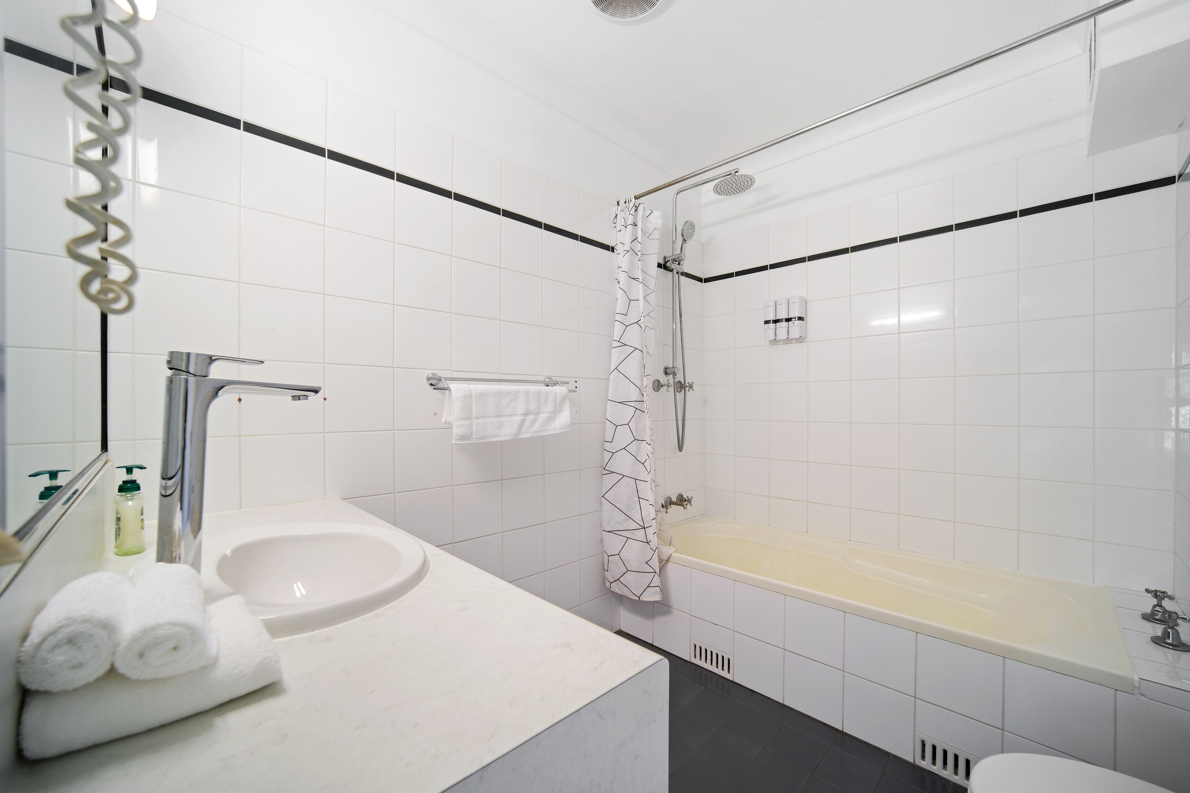Un baño moderno con lavamanos blanco, bañera y ducha.