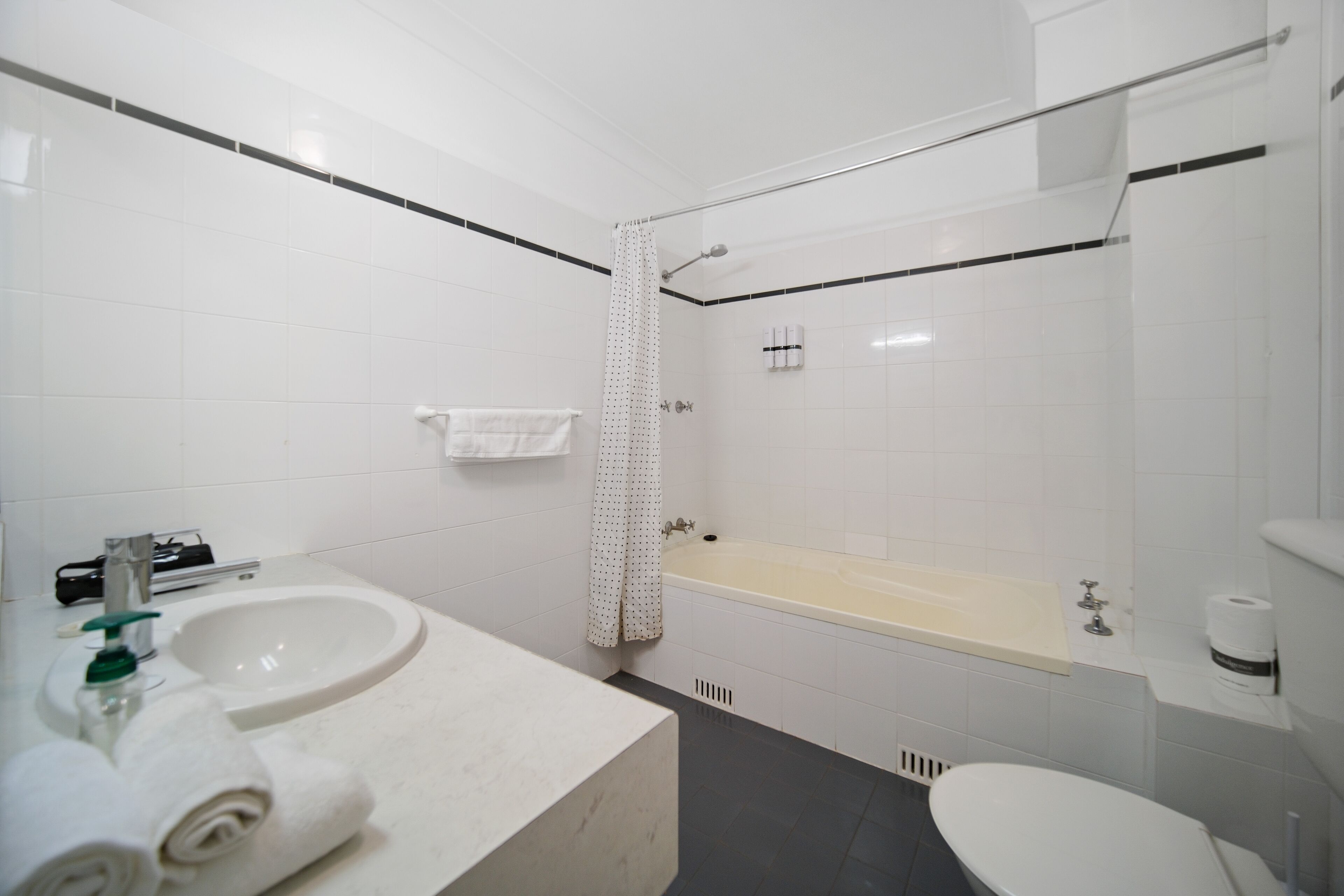 Een moderne badkamer met een wastafel, toilet, bad en douchegordijn.