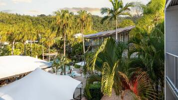 A resort with a pool area, palm trees, and a building with a white roof.