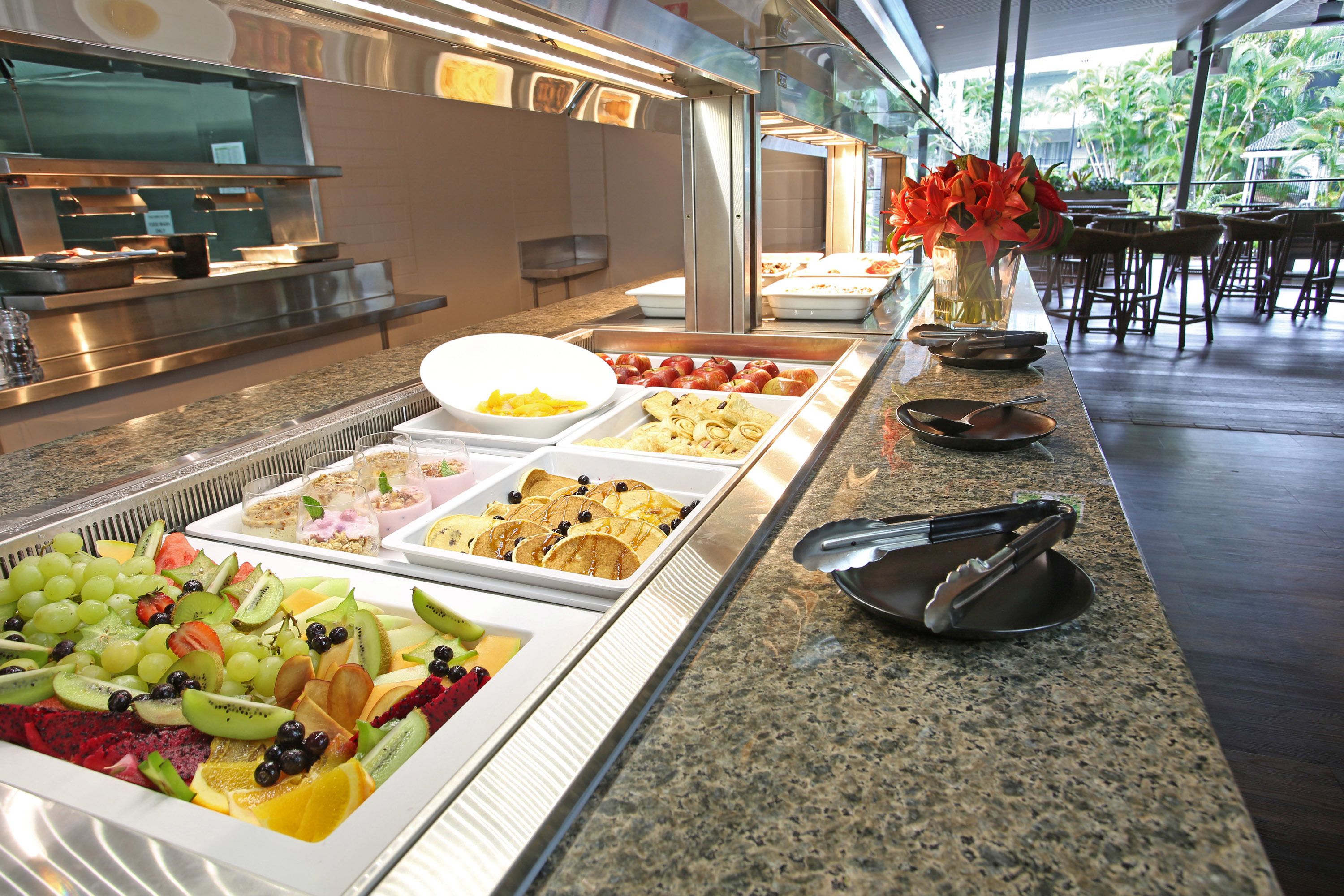 A buffet with various food options including fruits, pastries, and desserts.