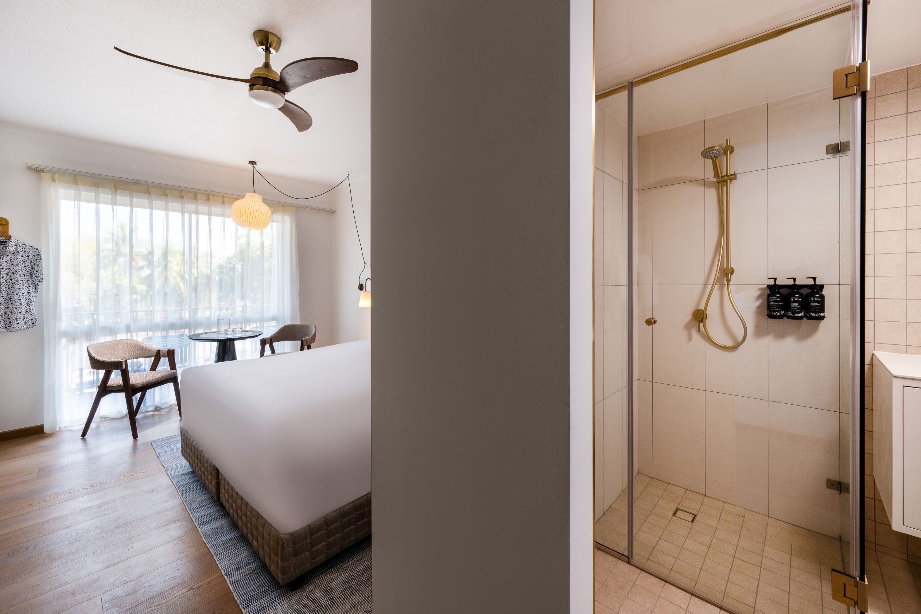 A hotel room with a bed, a desk, a chair, a ceiling fan, and a window with curtains.