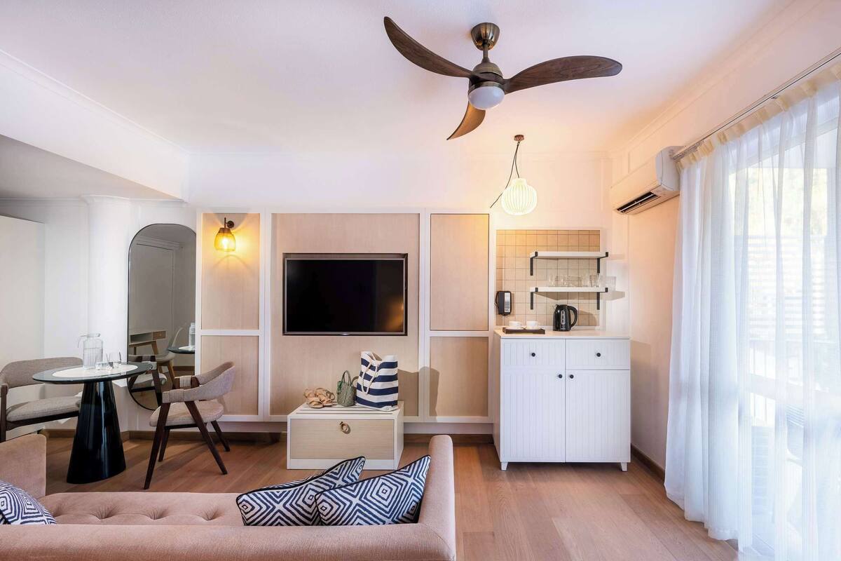 A modern living room with a sofa, TV, and a ceiling fan.
