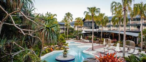 A resort with a swimming pool, palm trees, and lounge chairs.