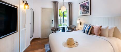 Une chambre d’hôtel avec un grand lit, un ventilateur de plafond, une télévision, une table à manger avec des chaises et une vue sur l’extérieur.