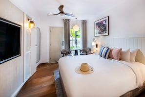 A hotel room with a large bed, a ceiling fan, a TV, a dining table with chairs, and a window with curtains. - Mantra Club Croc (Cannonvale)