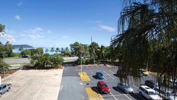 Un parking avec des places délimitées, dont des places réservées aux personnes handicapées, et une vue sur une étendue d’eau et une zone verdoyante en arrière-plan.