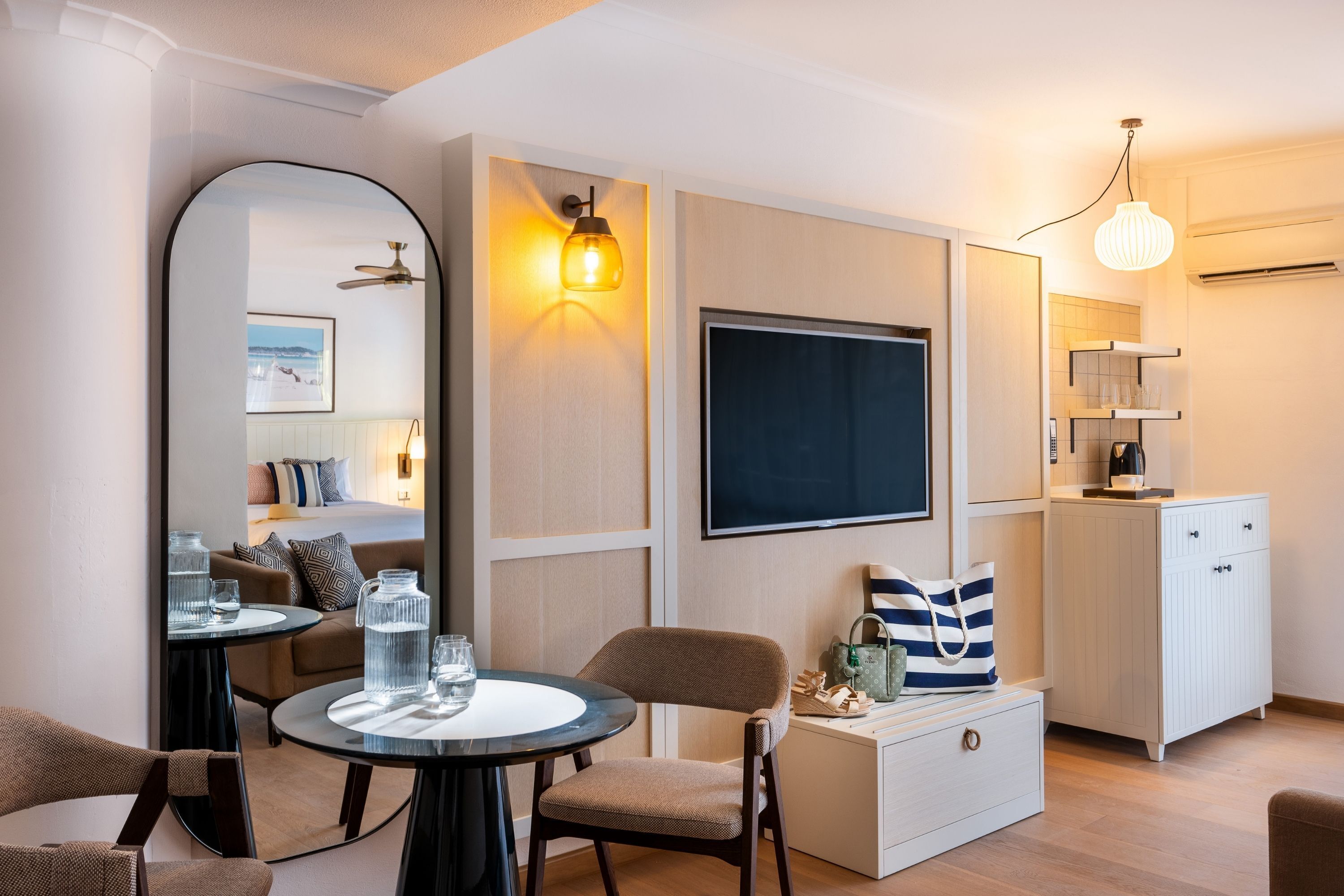 Ett modernt hotellrum med ett runt bord, en bekväm fåtölj, en stor spegel, en platt-TV, en minibar och en takfläkt.