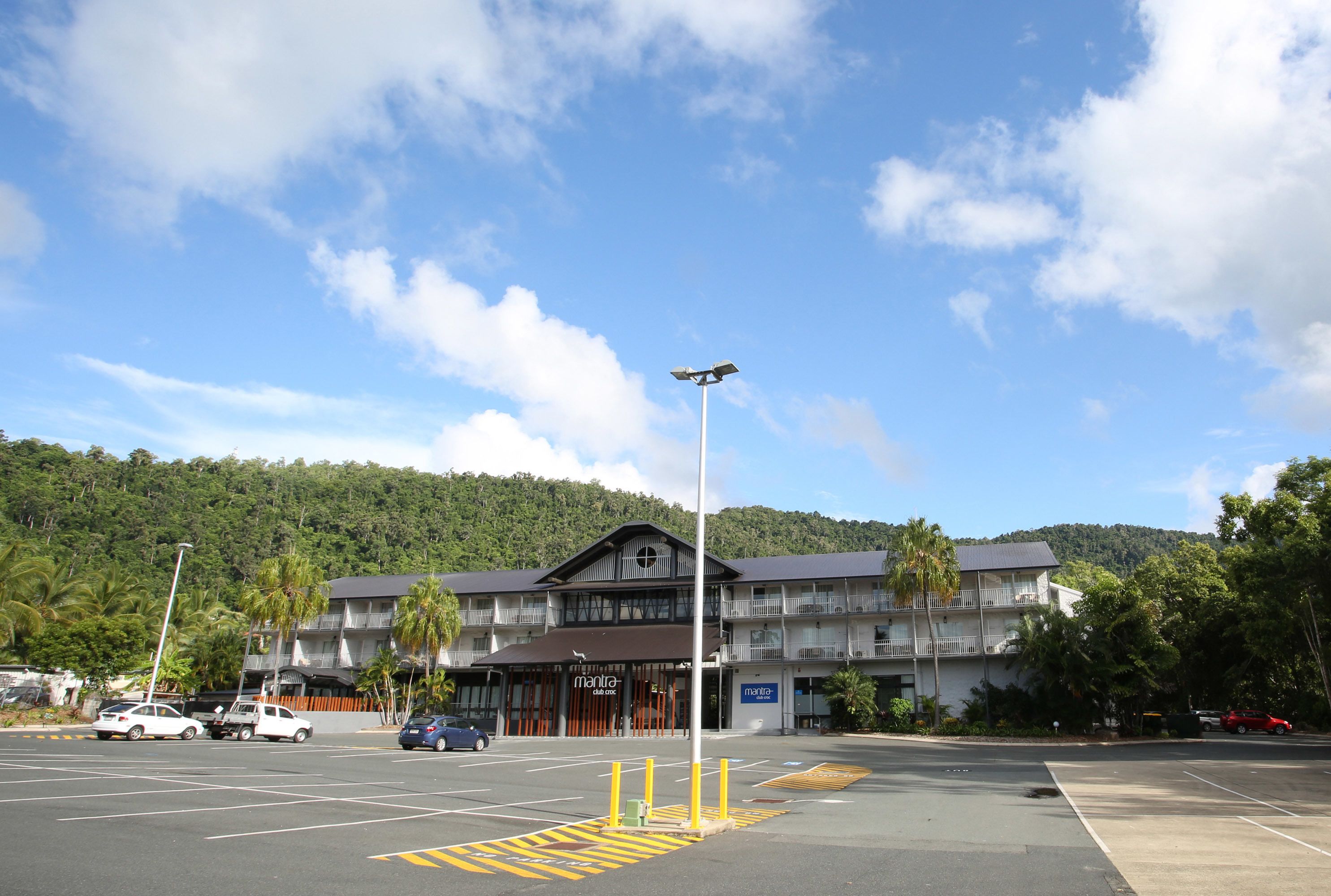 Un hôtel à plusieurs étages, doté d’une entrée principale, d’un parking et surplombant un paysage montagneux.