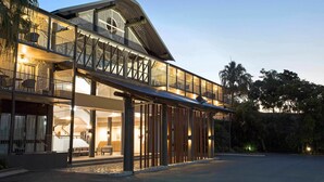 Un hotel moderno con fachada de vidrio, asientos al aire libre y un pasillo cubierto.