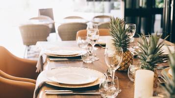 A dining table set with plates, cutlery, glasses, and candles, with chairs around it.