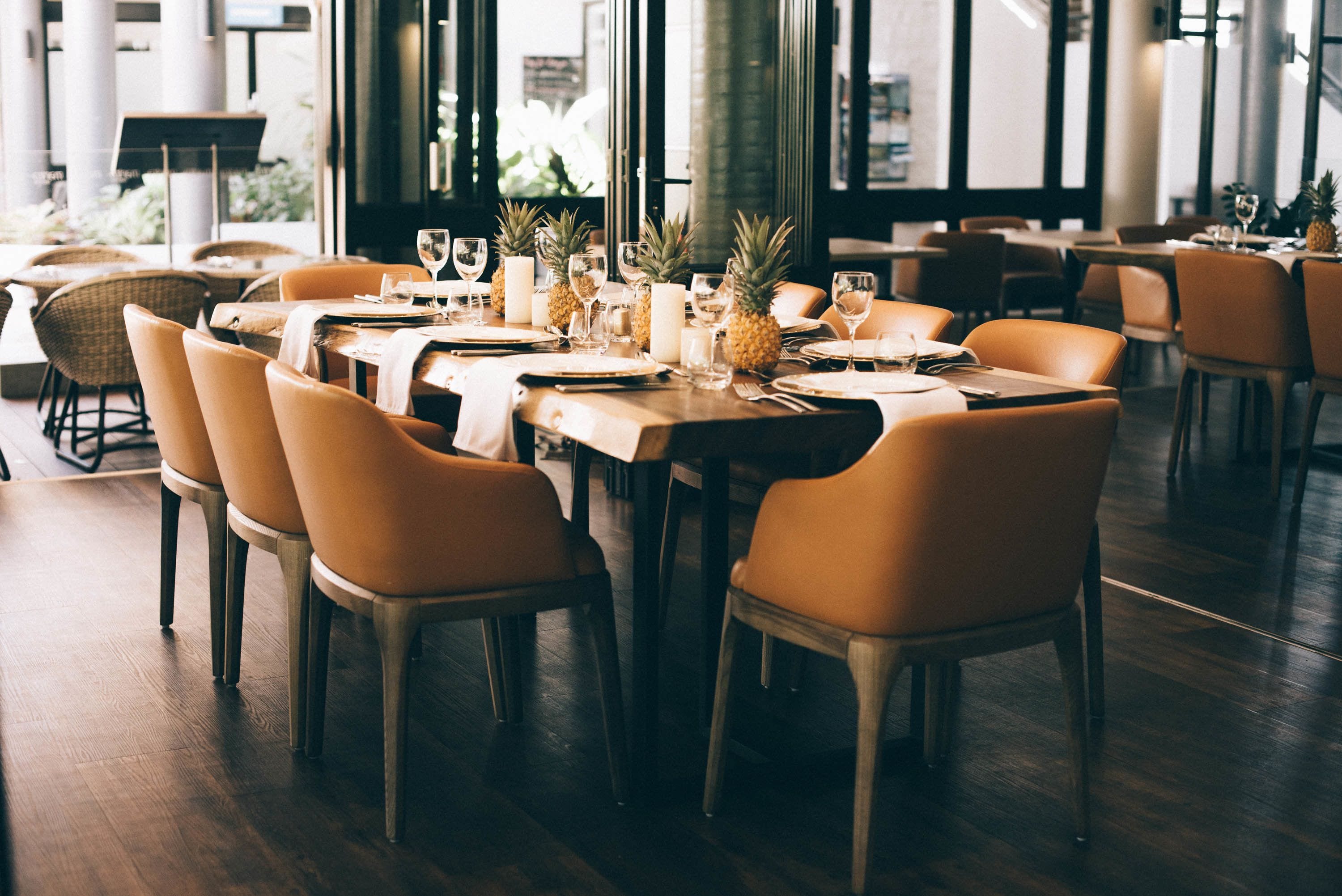 Un restaurante con mesas y sillas de madera, dispuesto para comer.