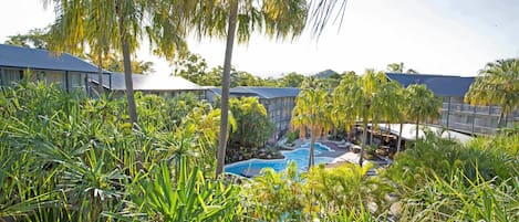 A resort with a swimming pool surrounded by lush tropical vegetation.