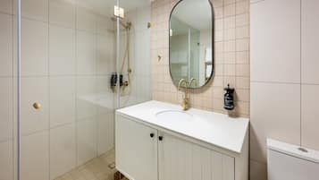 A modern bathroom with a white vanity, a large mirror, and a shower.