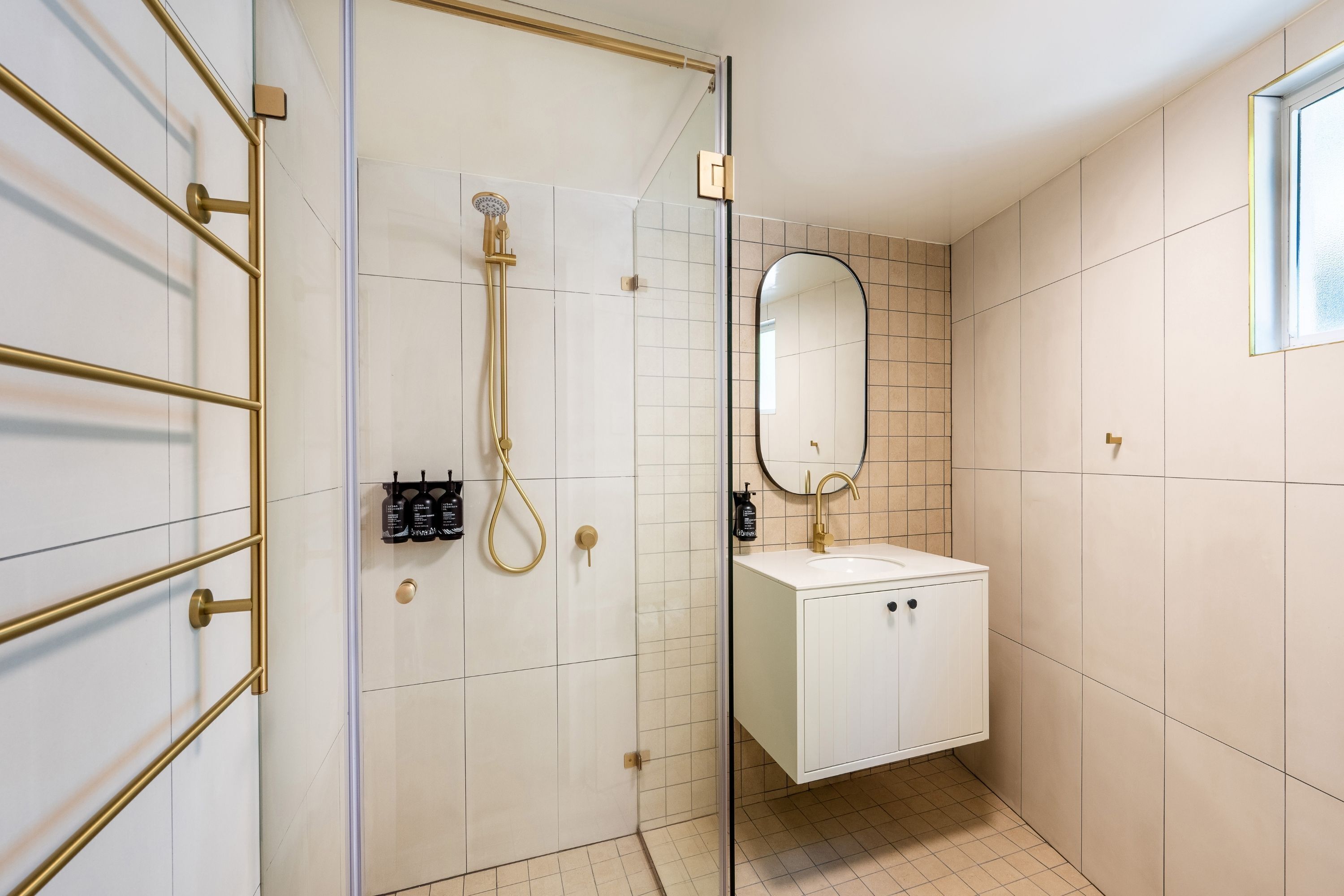 A modern bathroom with a glass shower enclosure, a white sink, and a mirror.