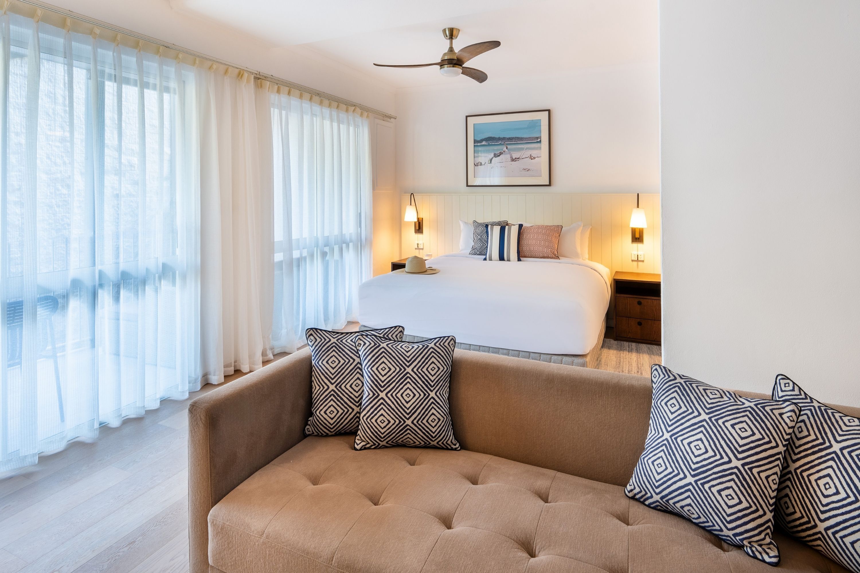 Una habitación de hotel con cama, sofá y ventilador de techo.