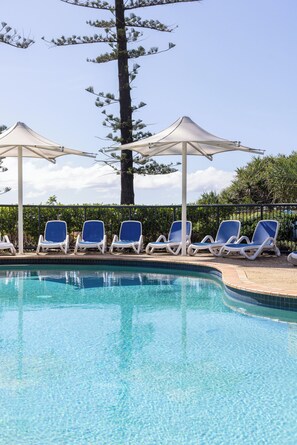 Una piscina con sillas de descanso y sombrillas.