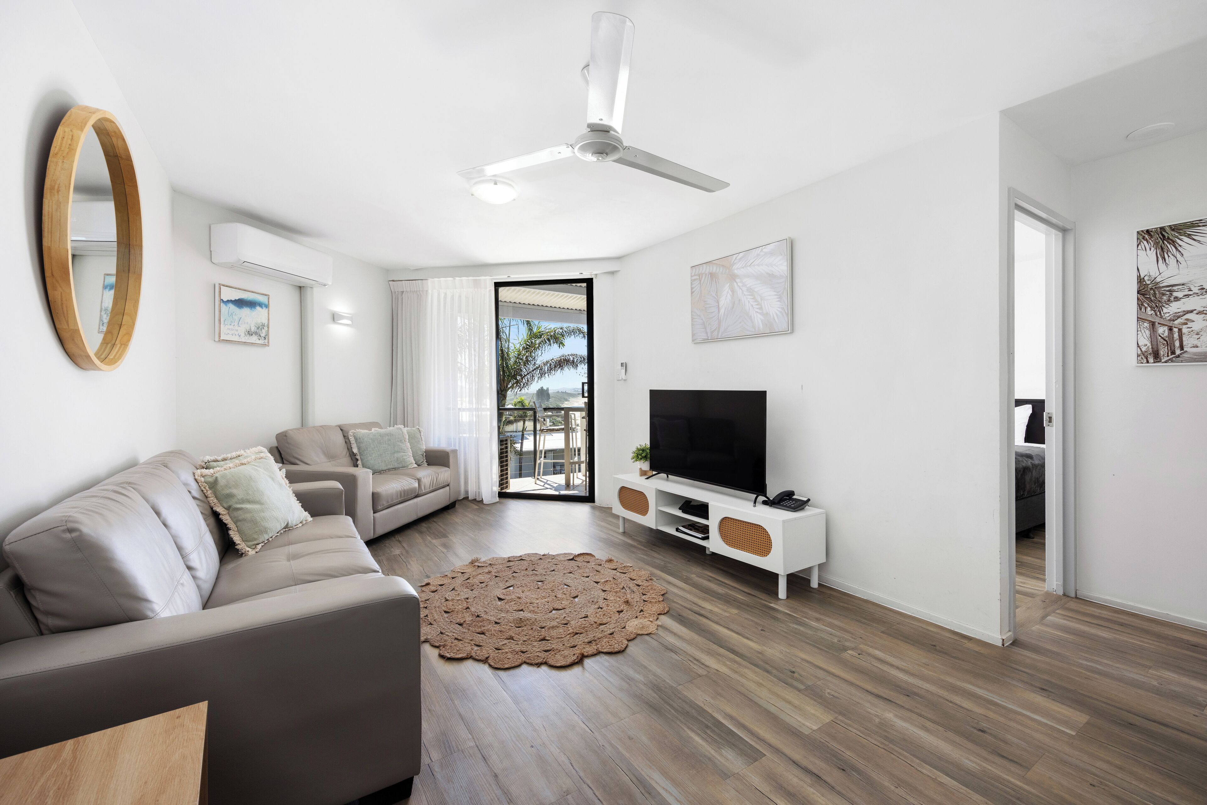 A modern living room with a sofa, TV, and ceiling fan.
