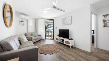 A modern living room with a sofa, TV, and ceiling fan.