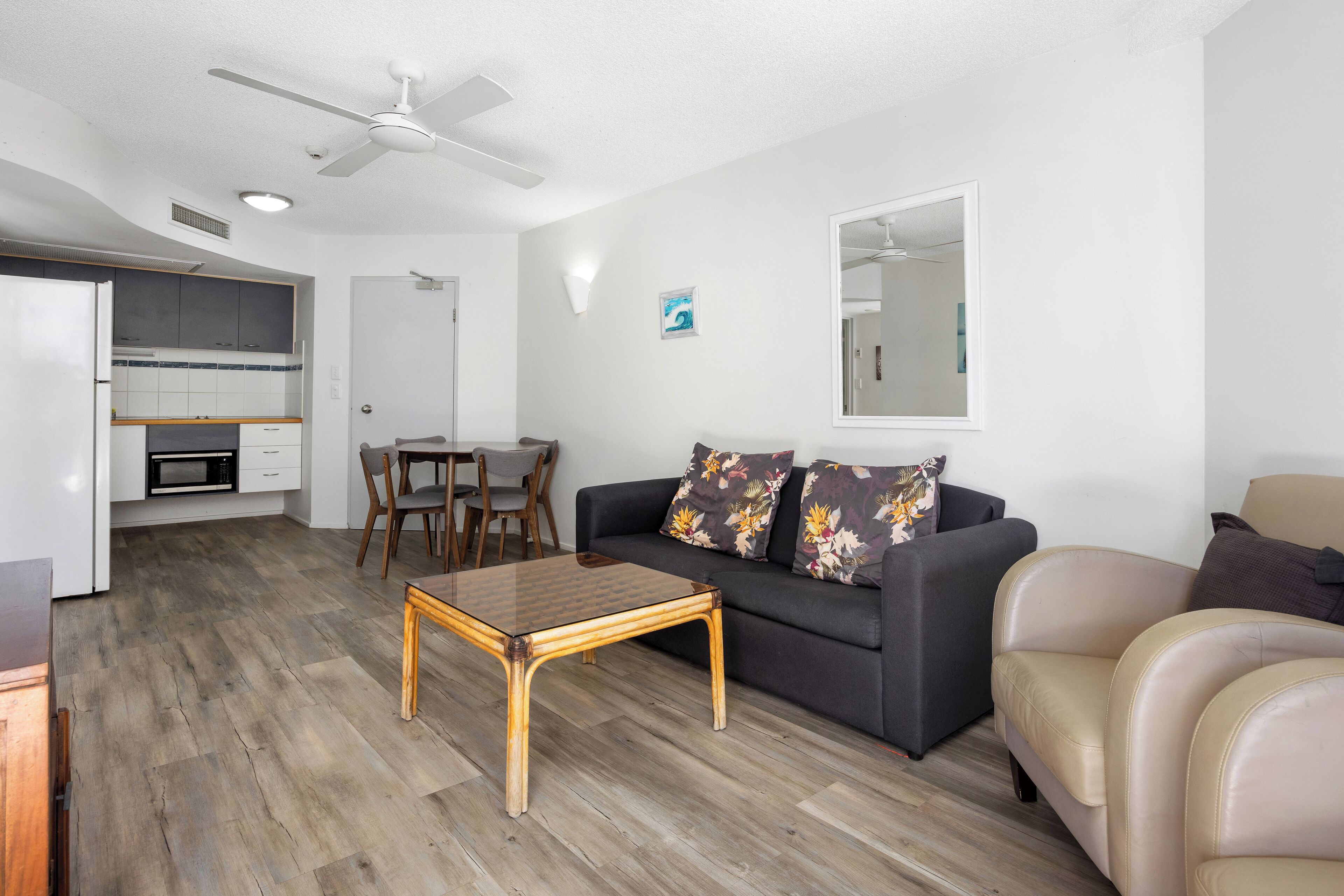 A modern living room with a sofa, a coffee table, and a dining area with chairs.