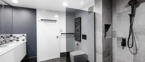 Et moderne badeværelse med bruser, toilet og badekar.