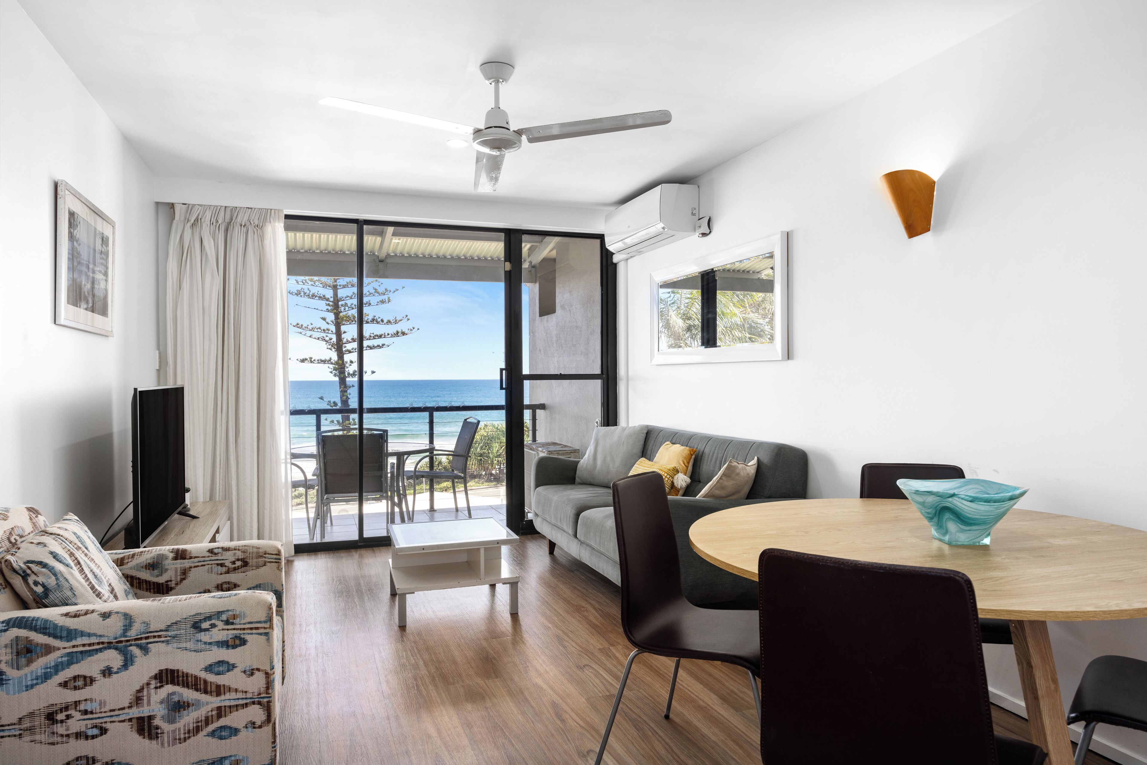 A modern living room with a sofa, a dining table, and a view of the ocean.