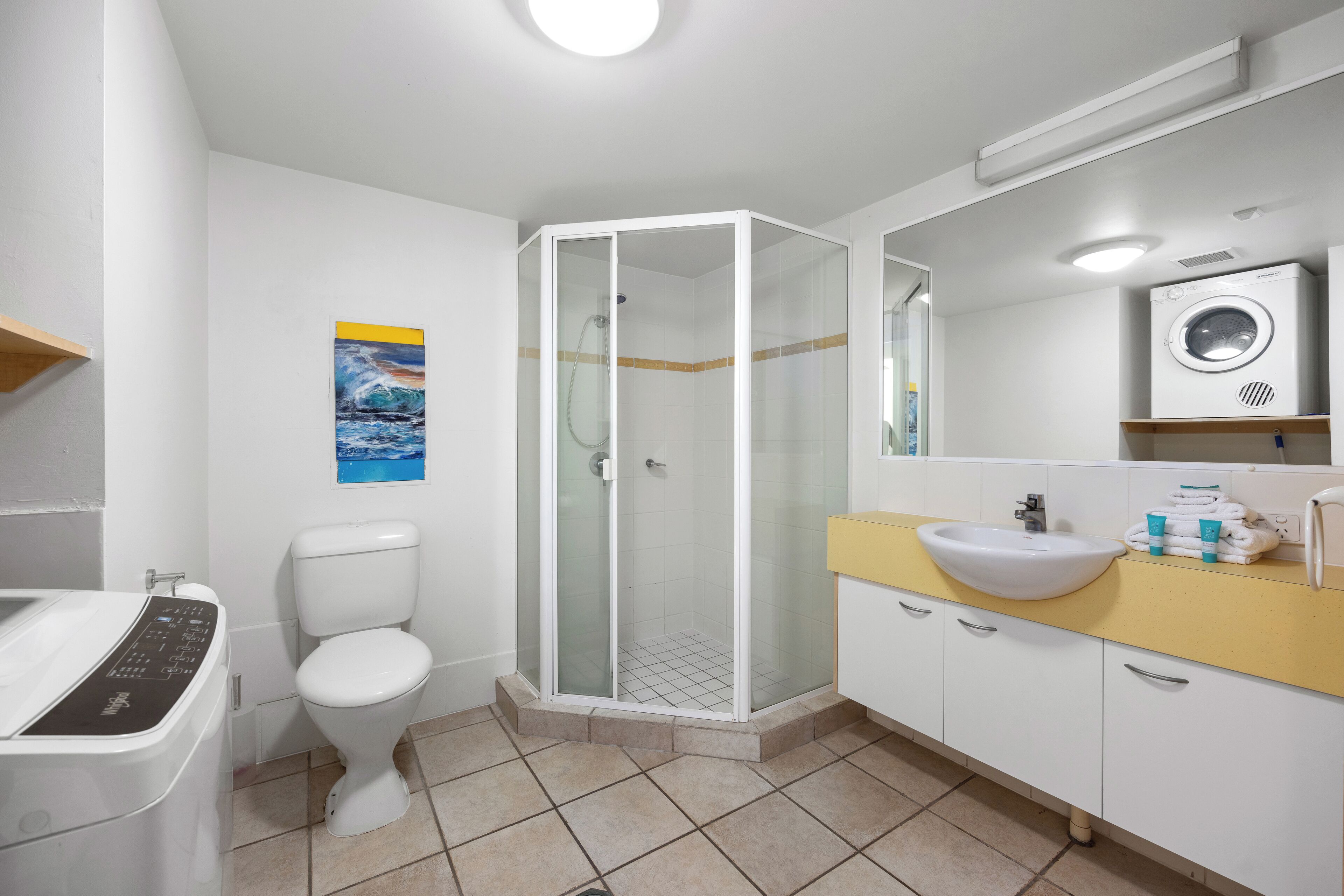 A modern bathroom with a glass-enclosed shower, a toilet, a sink, and a washing machine.