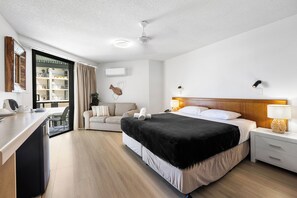Una habitación de hotel moderna con cama, mesitas de noche, escritorio y kitchenette.