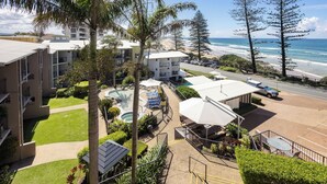 A hotel with a pool, outdoor seating, and a view of the beach and ocean. - Beach Retreat Coolum (Coolum Beach)