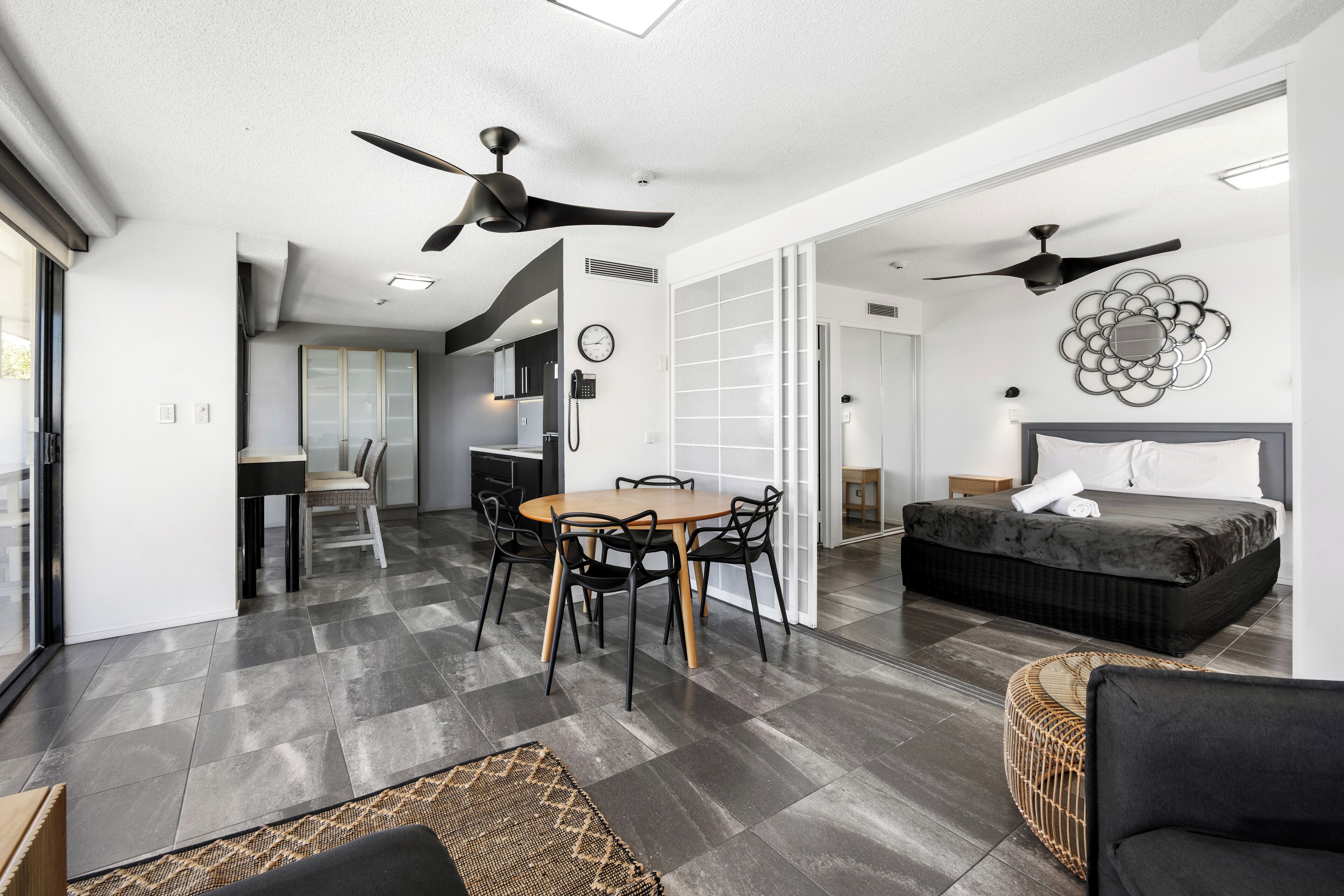 A modern living room with a dining area, a sofa, and a ceiling fan.