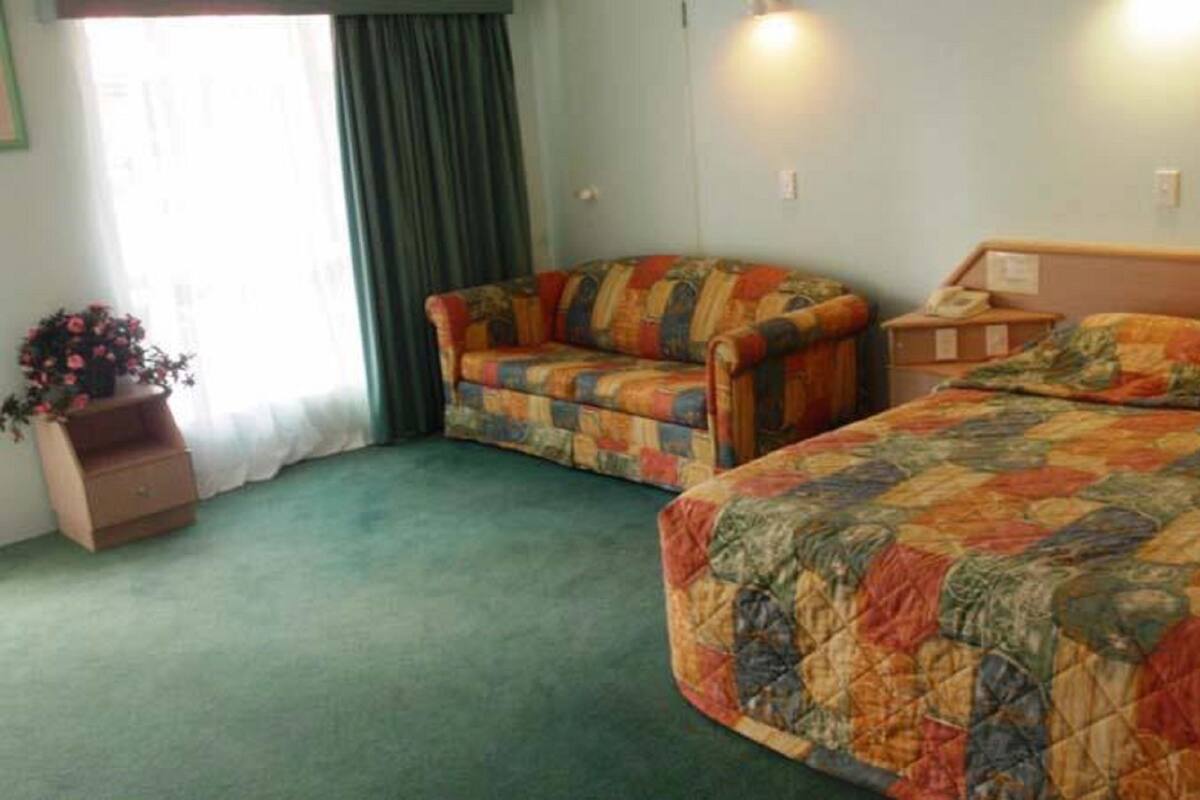 Una habitación de hotel con una cama, un sofá y una pequeña mesa con un teléfono.