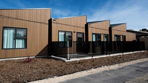 A modern building with a wooden facade, large windows, and a black fence. - Keith Motor Inn (Keith)