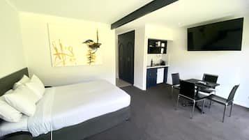 Ein modernes Hotelzimmer mit Bett, Schreibtisch und Fernseher.