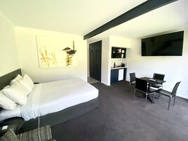 Habitación de hotel moderna con cama, escritorio y televisor.